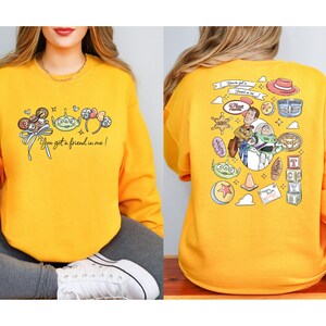 Disney Pixar Toy Story sweatshirt and hoodie featuring Woody, Buzz Lightyear, Rex, Hamm and Pizza Planet inspired design. Cozy unisex crewneck sweatshirt perfect for Disney park trips, Pixar fans, and family matching outfits. Soft and comfortable Disney sweatshirt ideal for Disneyland or Disney World vacations, travel days, or casual wear. Fun Toy Story sweatshirt great for kids at heart and Disney lovers.