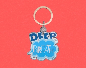 May include: A blue and white keychain with a gold ring. The keychain features a blue cloud with the words "DEEP BREATH" in white letters.