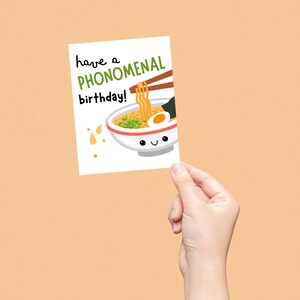 Funny birthday card with a cute smiling pho noodle bowl and the phrase "Have A Phonomenal Birthday", perfect for foodies, pho lovers, and pun lovers, ideal for sending fun and unique birthday wishes.