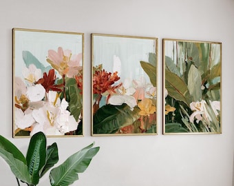May include: Three framed floral art prints. Each print features a different arrangement of flowers in shades of white, pink, red, and yellow, with green foliage against a light blue background. The frames are gold.