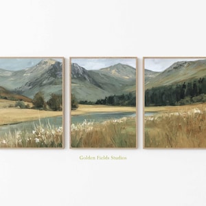 Peut inclure: Ensemble de trois peintures de paysages encadrées. Chaque œuvre représente une chaîne de montagnes, un plan d'eau et des champs d'herbes hautes. La palette de couleurs comprend des verts, des bruns et des bleus, avec un cadre neutre. Le texte "Golden Fields Studios" est visible.