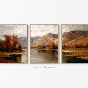 May include: A triptych of framed landscape prints. Each print depicts a tranquil scene with water, mountains, and trees. The colour scheme includes muted browns, greens, and greys, giving a vintage feel. The prints are in wooden frames.