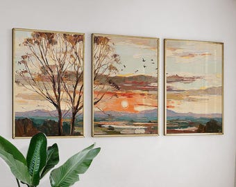 Puede incluir: Tres pinturas de paisajes enmarcadas con marcos dorados. La obra representa una puesta de sol sobre una cordillera, con árboles en primer plano. La paleta de colores incluye tonos de naranja, amarillo, marrón y azul.