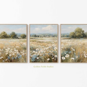 Peut inclure: Ensemble de trois impressions d'art encadrées représentant des paysages. Chaque œuvre montre un champ de fleurs sauvages dans un style impressionniste. Palette de beiges, bleus et verts, ciel bleu clair et cadre en bois. Texte "Golden Fields Studios".