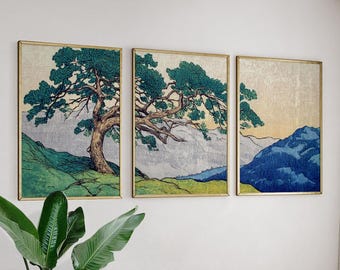 May include: A triptych of framed art prints depicting a Japanese landscape. Each print shows a tree with green leaves, mountains, and a muted colour scheme of greens, blues, and beige. The frames have a gold finish.