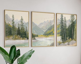 Op de afbeelding: Set van drie ingelijste landschapsschilderijen. Elk toont een berglandschap met een rivier en groenblijvende bomen. De kunstwerken hebben een gouden lijst en een neutraal kleurenpalet met groen, blauw en beige tinten.