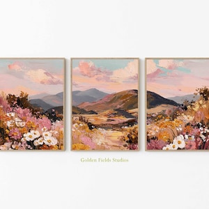Op de afbeelding: Set van drie ingelijste landschapsschilderijen. Elk toont een berglandschap in pastelkleuren van roze, geel en blauw. De kunstwerken bevatten bloemen en een gestructureerde, impressionistische stijl.