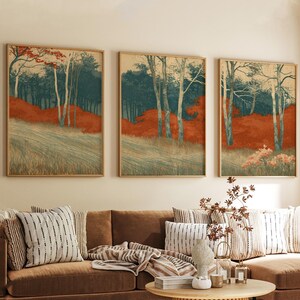 Peut inclure: Un ensemble de trois impressions murales rectangulaires dans des cadres en bois clair, représentant chacune un paysage forestier avec de grands arbres, un feuillage vert foncé et des sous-bois orange vif sur un fond pâle.