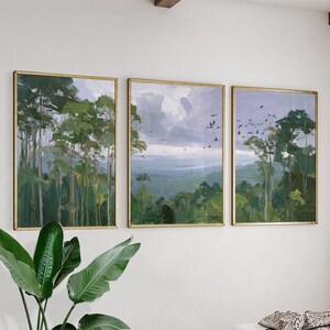 May include: A triptych of framed landscape paintings. Each artwork depicts a forest scene with tall green trees and a cloudy sky. The frames are gold-coloured, and the paintings have a soft, painterly style.