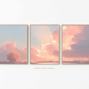 Op de afbeelding: Set van drie ingelijste kunstdrukken met een pastelkleurige lucht met pluizige roze wolken en een boom. Het kunstwerk heeft een zachte, dromerige esthetiek, met een lichtblauwe lucht en een vleugje landschap onderaan. De tekst "Golden Fields Studios" staat onderaan.