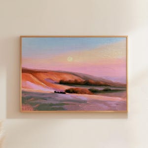May include: A rectangular landscape painting featuring rolling hills under a soft sunset sky. The scene displays shades of pink, orange, and lavender, with a pale yellow sun centred above the horizon. Dark patches of vegetation dot the foreground.