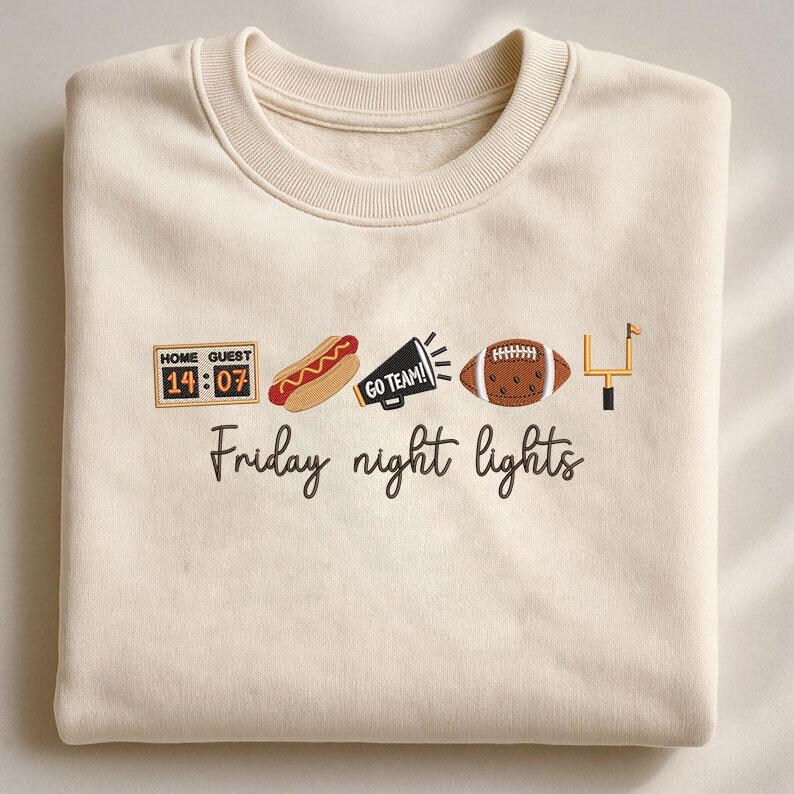 Op de afbeelding: Een cr&egrave;mekleurige sweater met ronde hals en geborduurde iconen, waaronder een scorebord met 14:07, een hotdog, een megafoon met de tekst GO TEAM!, een football en een doelpaal, met de tekst Friday night lights eronder geborduurd.