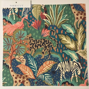 May include: A colorful fabric featuring a jungle scene with a leopard, zebra, giraffe, and peacock. The fabric has a dark blue background with green, orange, and white accents. The text "FABRICUT" is printed on the top of the fabric.