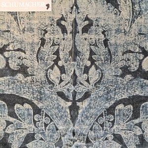 May include: A blue and white fabric with a damask pattern. The fabric has a distressed look, with the white pattern appearing faded and worn. The fabric is from Schumacher.