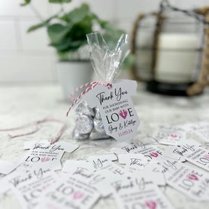 May include: White and pink baby shower favor tags with the text "Thank You for showering our baby with love" and the names "Greg & Katelyn" and the date "11.09.24".