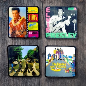 以下が含まれることがあります： 象徴的な音楽イメージが特徴の4つの正方形パッチ。1つのパッチには、テキスト「Elvis Blue 14 Great Songs」とエルビス・プレスリーが描かれています。別のパッチには、テキスト「Elvis Presley」とギターを演奏するエルビスが描かれています。3つ目のパッチは、アビーロードを横断するビートルズを描いています。最後のパッチは、テキスト「Yellow Submarine」とビートルズを描いています。