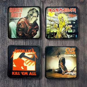以下が含まれることがあります： ロックバンドのアルバムアートが描かれた正方形のパッチ4枚。Quiet Riot、Iron Maiden、Metallica、Ozzy Osbourneの画像が含まれています。各パッチは黒い縁取りがあり、木製の背景に配置されています。