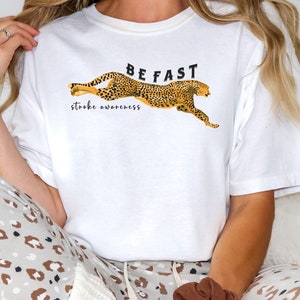 May include: White t-shirt with a cheetah print design and the text "BE FAST stroke awareness".