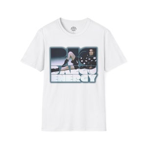 May include: White t-shirt with a graphic print of a person in a black and white patterned outfit. The graphic text reads "BIG ENERGY".