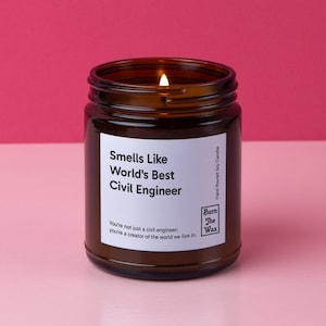 May include: A brown glass candle jar with a white label that reads "Smells Like World's Best Civil Engineer". The label also includes the text "You're not just a civil engineer; you're a creator of the world we live in." and the logo "Burn The Wax".