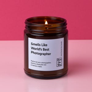 May include: A brown glass candle jar with a white label that reads "Smells Like World's Best Photographer". The label also includes the text "You're not just a photographer, you're a visual poet and a memory maker." and the logo "Burn The Wax".