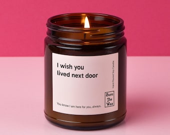 Könnte beinhalten: Ein braunes Glasgefäß mit einer Kerze und einem weißen Etikett mit dem Text "I wish you lived next door". Das Etikett enthält auch den Text "You know I am here for you, always." und das Logo "Burn The Wax" mit dem Text "Hand Poured Soy Candle".