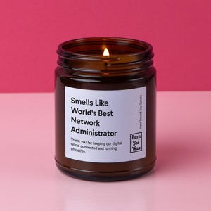 May include: A brown glass candle jar with a white label that reads "Smells Like World's Best Network Administrator". The label also includes the text "Thank you for keeping our digital world connected and running smoothly." and the logo "Burn The Wax".