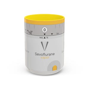Op de afbeelding: Een wit en grijs medisch apparaat met een gele bovenkant. Het apparaat heeft een wijzerplaat met een naald die "0" aangeeft en de tekst "Sevoflurane vapor".