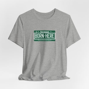 May include: Grey t-shirt with a green Vermont license plate design that says "Born Here - Green Mountain State".