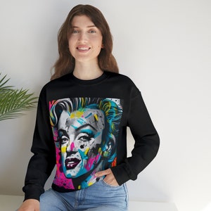 May include: Black sweatshirt with a colorful graphic print of Marilyn Monroe's face.
