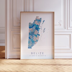May include: A framed print of a map of Belize with a blue and pink floral pattern. The map is surrounded by a gold frame and the text "BELIZE 17.1899° N, 88.4976° W" is printed below the map.