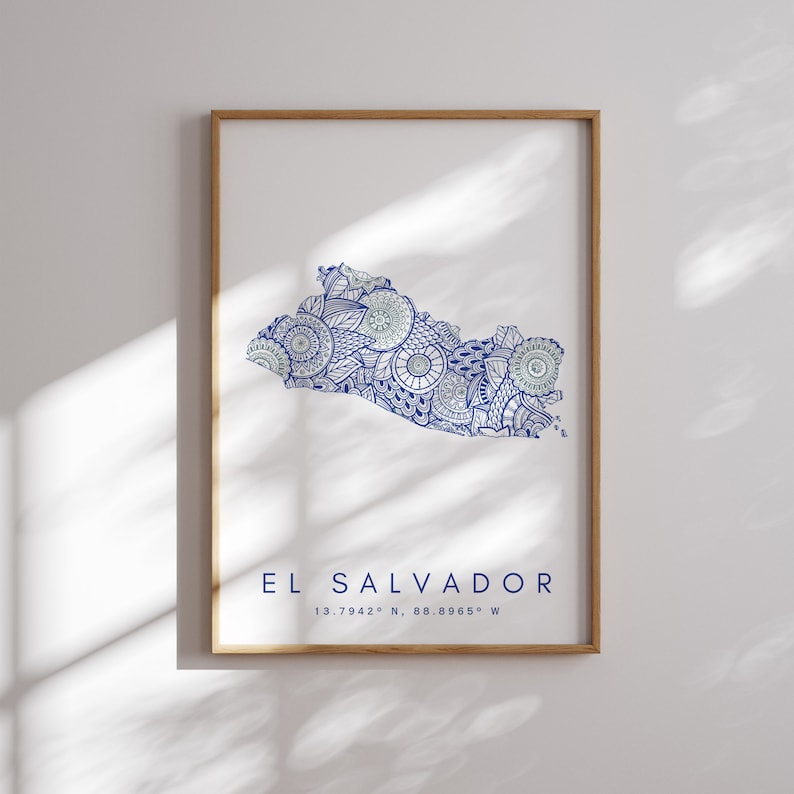 Peut inclure: Une impression encadr&eacute;e d'une carte stylis&eacute;e bleu et blanc du Salvador avec le texte "EL SALVADOR 13.7942&deg; N, 88.8965&deg; W" sous la carte.