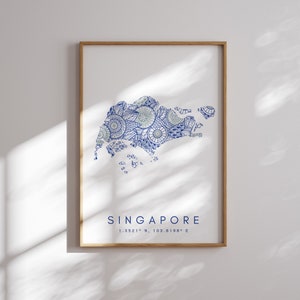 Op de afbeelding: Een ingelijste print van een blauw en groen mandala-ontwerp van het eiland Singapore. De print bevat de tekst "SINGAPORE" en de coördinaten "1.3521° N, 103.8198° E".