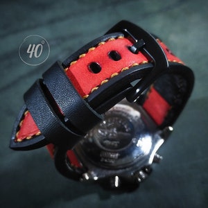 Pode incluir: Uma pulseira de relógio de couro preto com costuras vermelhas e uma fivela preta. A pulseira é projetada para um relógio com uma largura de lug de 20 mm.
