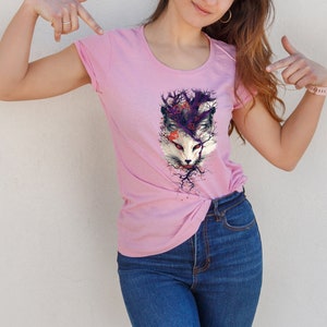 May include: A pink t-shirt with a graphic print of a white fox's face surrounded by purple and black branches.