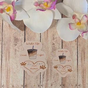 May include: Two brown and beige stickers with the text "Wake Up Drink Coffee Save Animals" and a cartoon image of a cup of iced coffee. The stickers are shaped like a heart with paw prints.