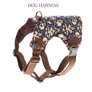 May include: Dog harness with a navy blue floral pattern and brown leather straps. The harness has a metal buckle and a metal ring for leash attachment. The text "DOG HARNESS" is at the top.