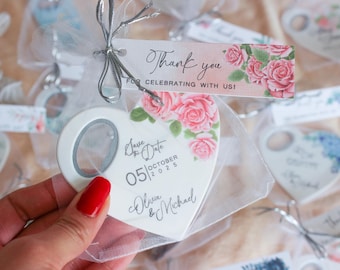 May include: White ceramic heart-shaped bottle opener with a floral design and the text "Save the Date 05|OCTOBER|2025 Olivia & Michael".
