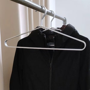 May include: A silver metal hanger with a black jacket hanging on it.