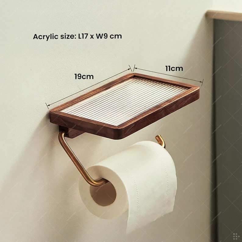 May include: A wooden and acrylic toilet paper holder with a shelf. The shelf is 19 cm long and 11 cm wide. The acrylic size is L17 x W9 cm. The holder has a gold-colored metal bar to hold the toilet paper roll.
