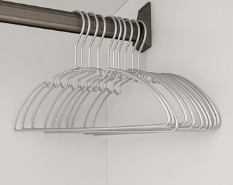 May include: A set of 10 silver wire hangers with a rounded shape. The hangers are hanging from a metal rod.