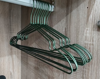 May include: A stack of 12 green wire hangers hanging from a metal rod in a closet.