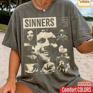 May include: Dark grey t-shirt with the word "SINNERS" in a white rectangular box. The shirt features a collage of black and white images of people. The text "Comfort COLORS" is in a red box.