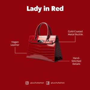 Pu&ograve; includere: Una borsa a mano in pelle vegana rossa con una fibbia in metallo dorato e dettagli cuciti a mano. La borsa ha una texture a coccodrillo in rilievo e un manico superiore.