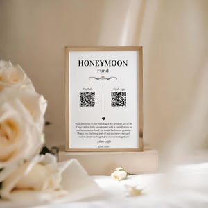 May include: A gold-framed sign with the text "Honeymoon Fund" and QR codes for PayPal and Cash App. The sign also includes the text "Your presence at our wedding is the greatest gift of all. If you wish to help us celebrate with a contribution to our honeymoon fund, we would be forever grateful. Thank you for being part of our journey - we can't wait to create unforgettable memories together!" and the date "25.07.2025".