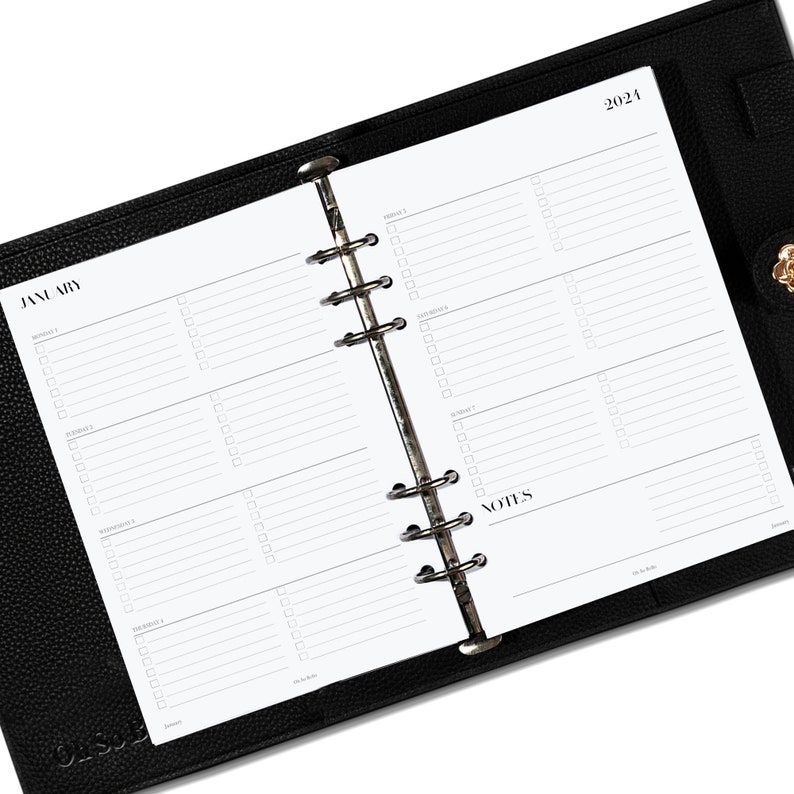 May include: A white planner with a black leather cover. The planner is open to January 2024 and has a daily layout with space for notes.