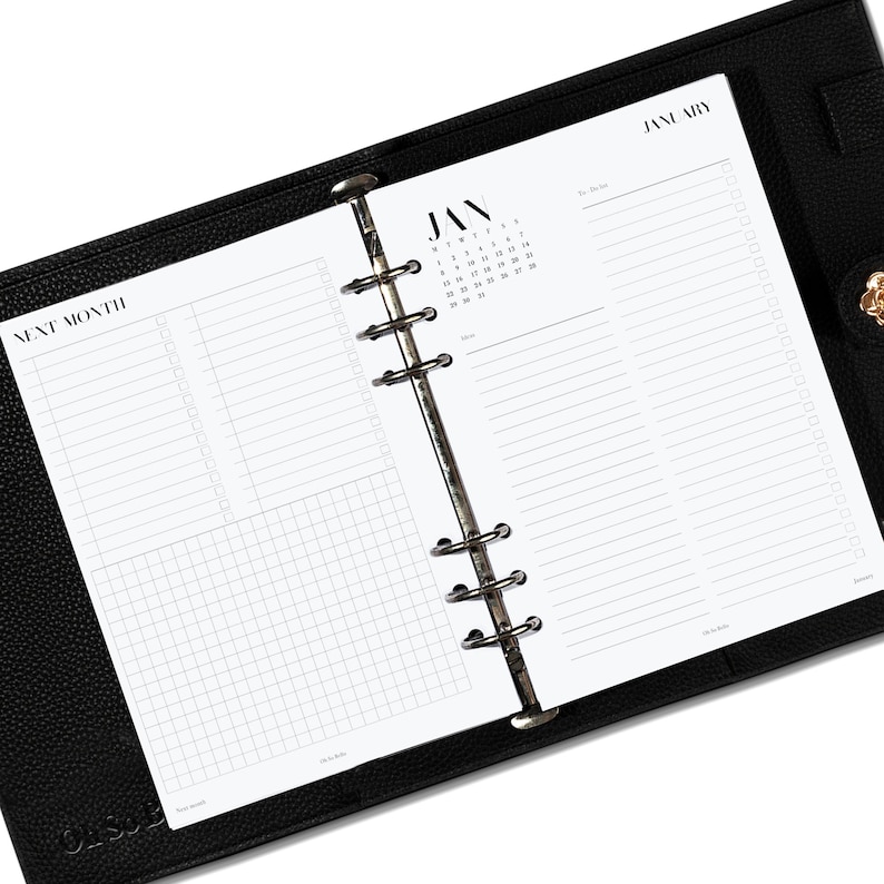 May include: A black leather bound planner with a white page open to January. The page has a calendar grid with the month of January and a to-do list section. The next page has a grid for notes and a section for next month.