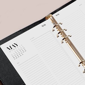May include: A black and white monthly calendar planner with a gold ring binder. The calendar is for the month of May and includes a to-do list and space for ideas.