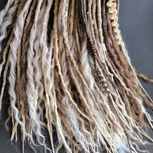 May include: A set of brown and white synthetic dreadlocks. The dreadlocks are made of a variety of textures, including straight, wavy, and curly. The dreadlocks are tied together at the top with a brown string.