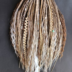 May include: A set of long, brown and blonde synthetic dreadlocks with white and beige accents. The dreadlocks are decorated with beads and feathers.